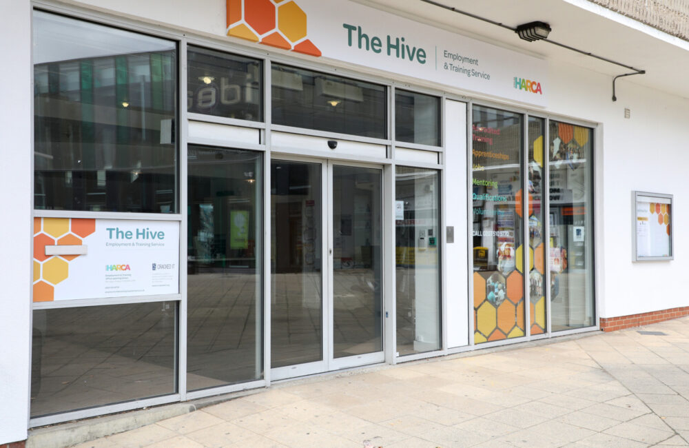 A picture of the Hive. A white building with an orange and yellow hive logo at the back.